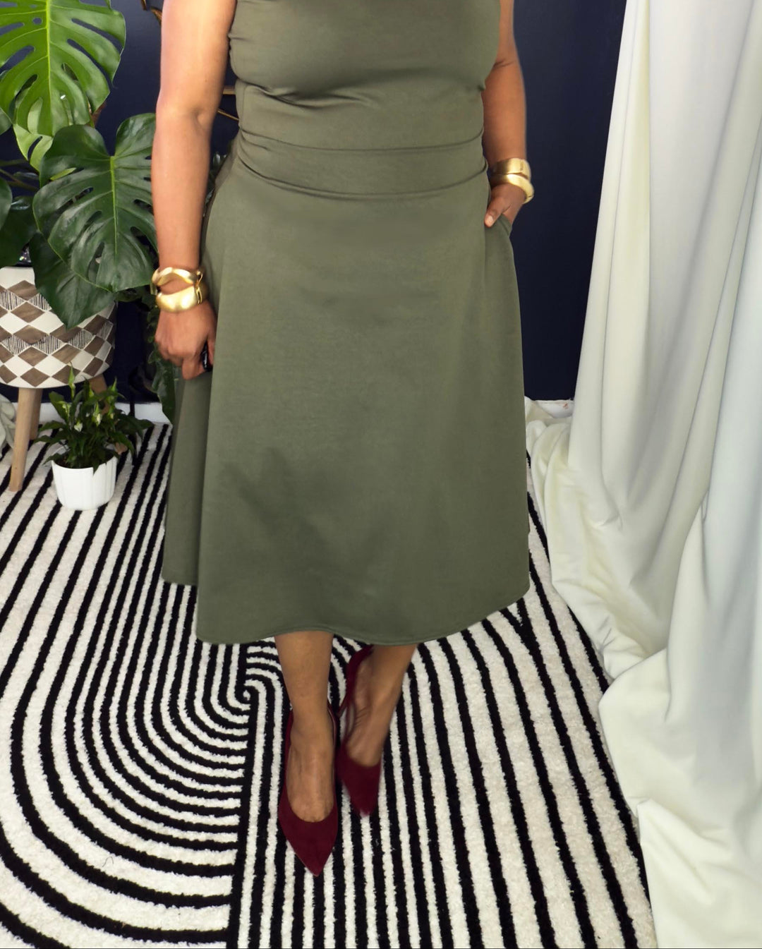 Woman in a green dress standing in a room with decorative elements.