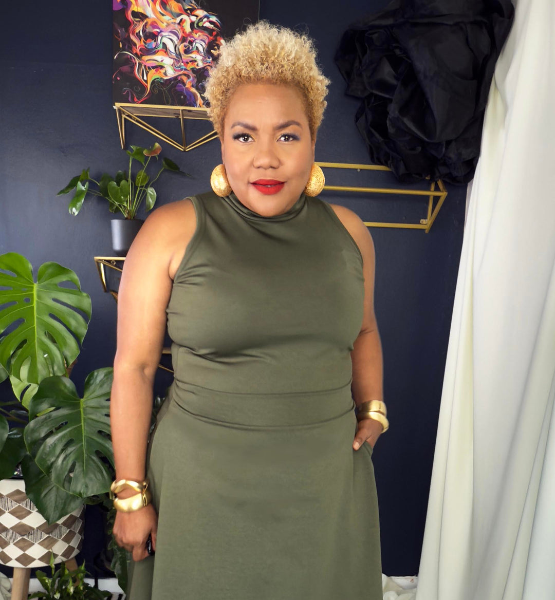 Woman in a green dress standing in a room with decorative elements.