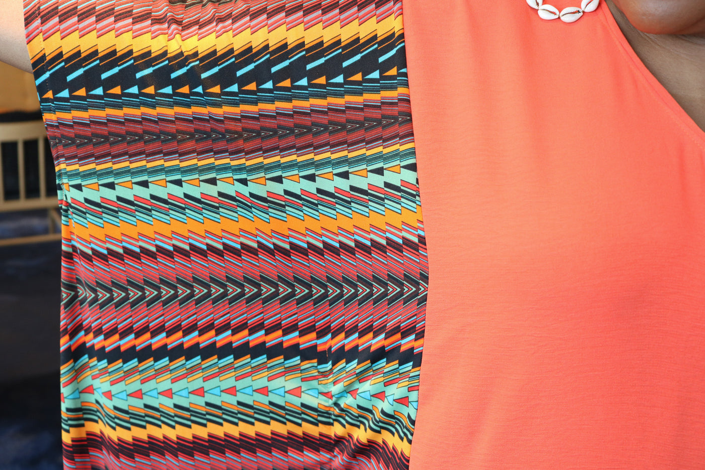 Colorful patterned sleeveless top with a plain orange sleeveless top underneath.