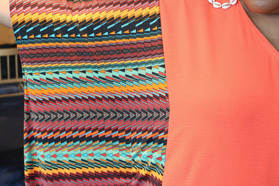 Colorful patterned sleeveless top with a plain orange sleeveless top underneath.