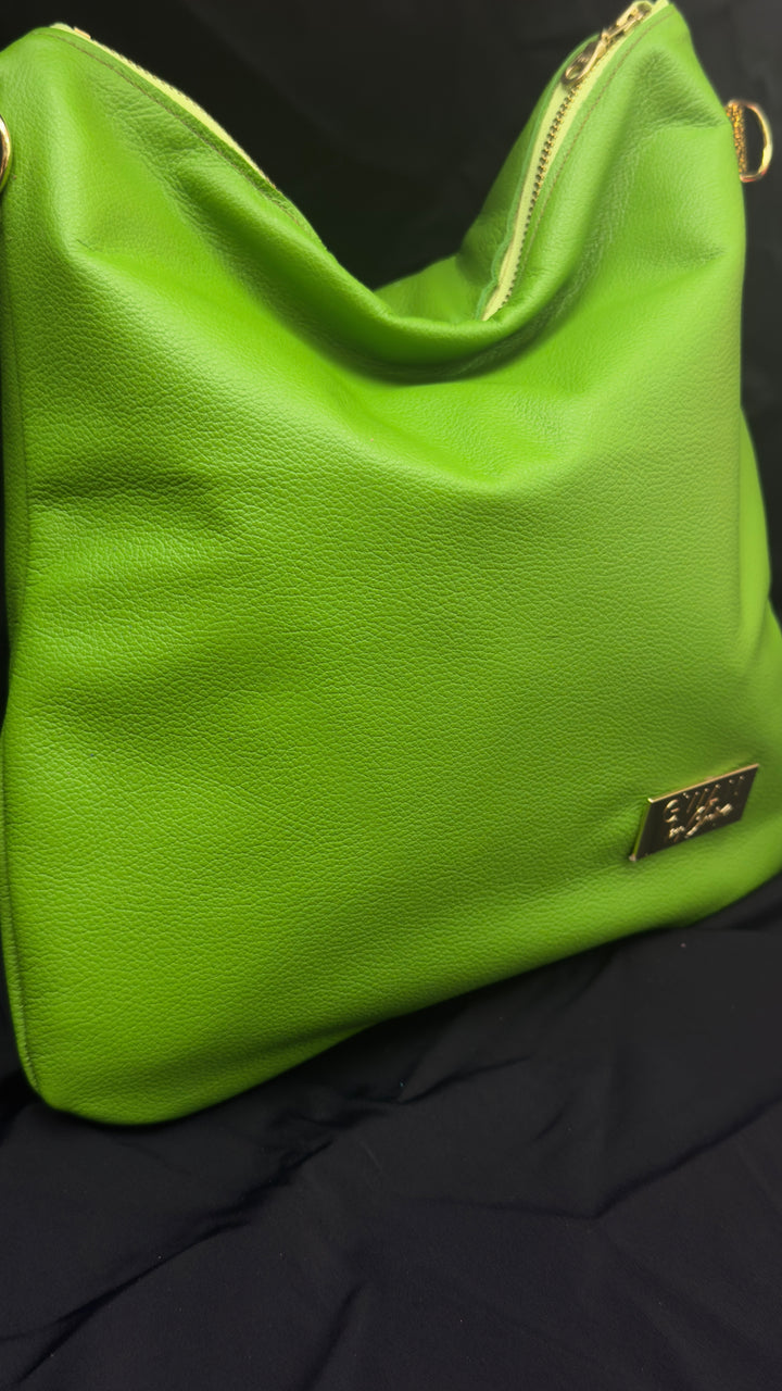 A bright lime green pebbled leather shoulder bag with gold-tone hardware, including a zipper and a small metal logo plaque, resting on a black fabric background.