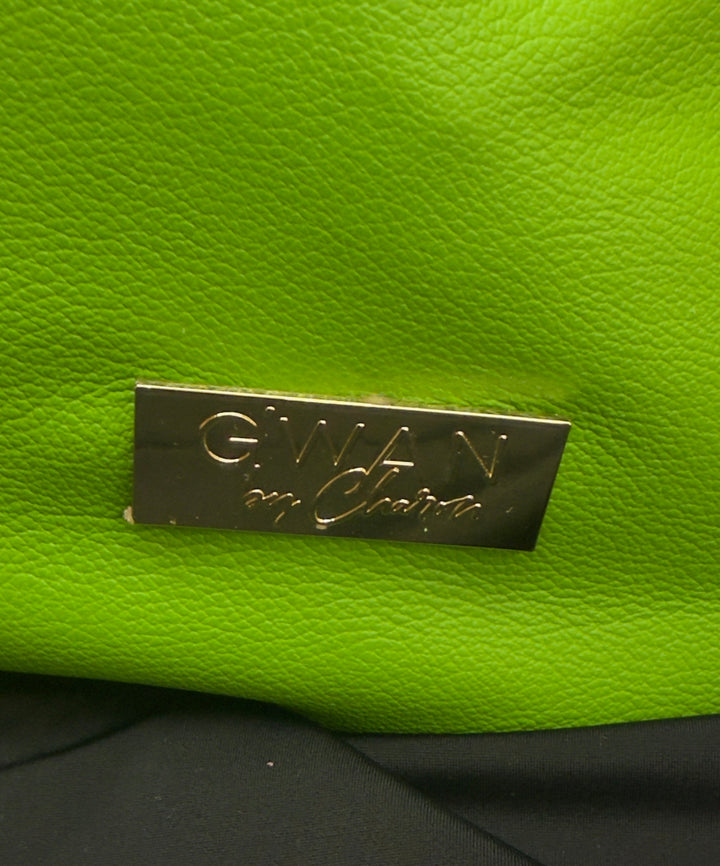 Close-up of a bright lime green textured leather bag with a silver-tone metal brand plaque reading 'GWAN on Garza'.