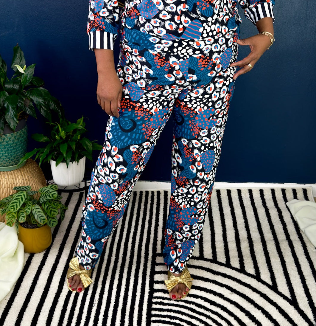 Woman wearing a colorful floral jumpsuit standing in a room with blue walls and striped floor.
